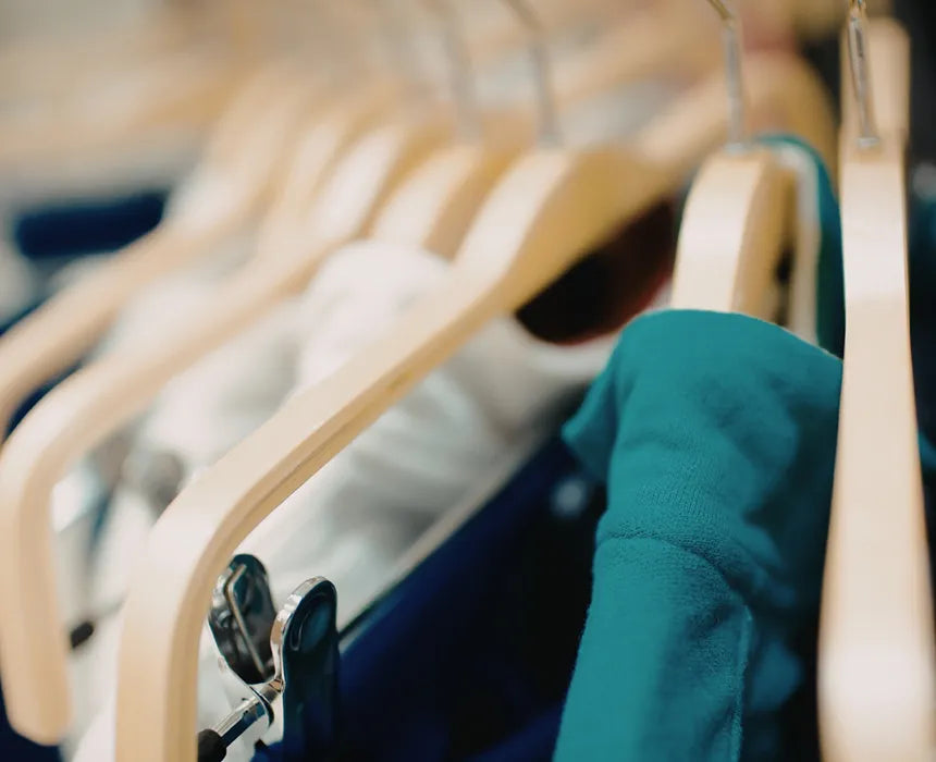 Close-up of wooden hangers with a teal garment on a blurred background